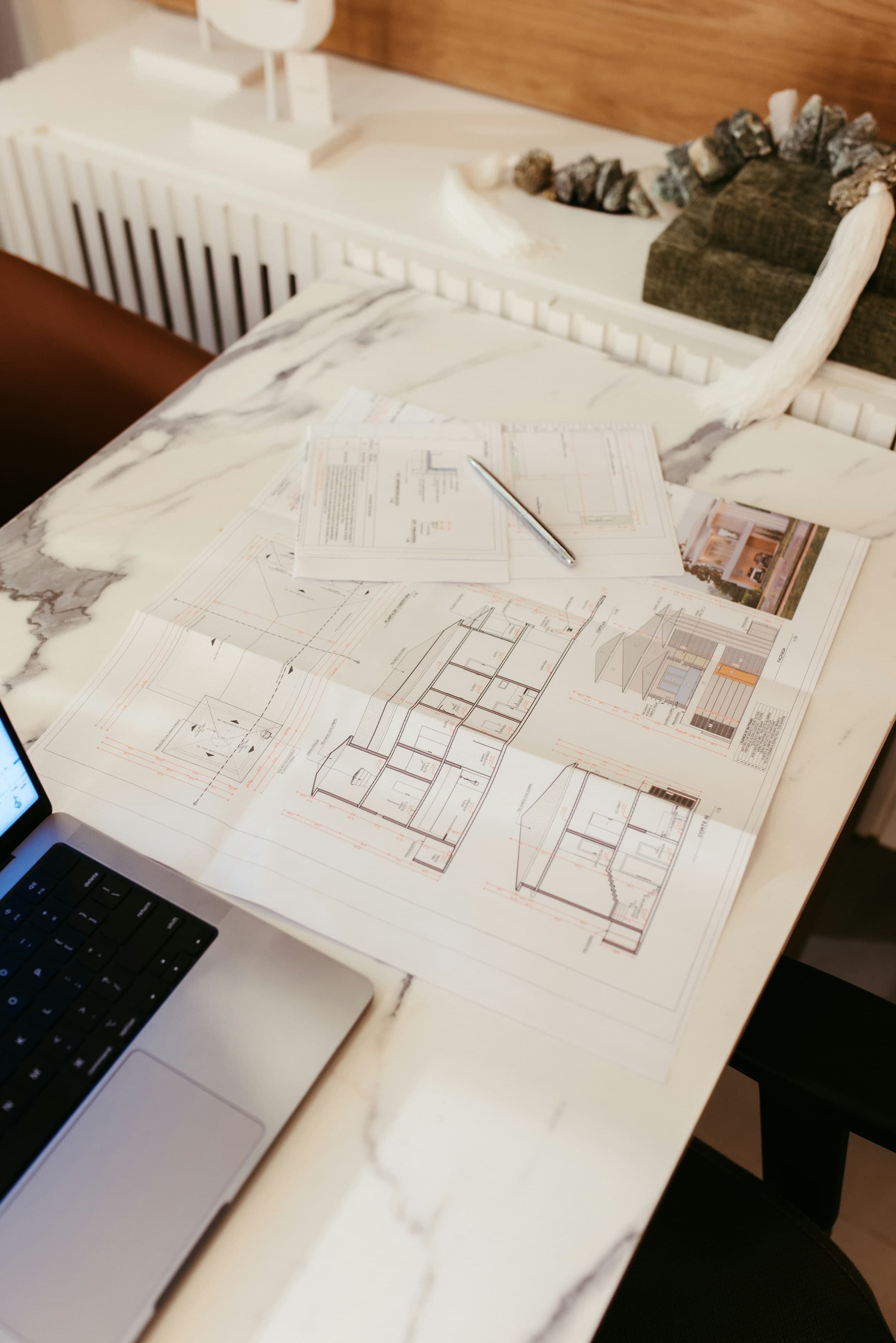 Architekturpläne und Laptop auf einem hochwertigen Arbeitstisch